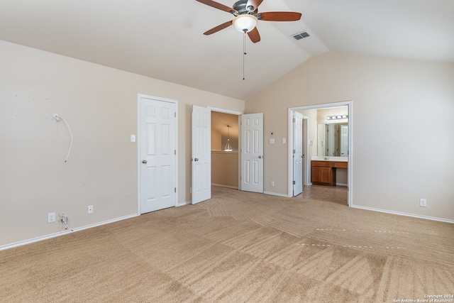 unfurnished bedroom with ceiling fan, light colored carpet, lofted ceiling, and ensuite bath