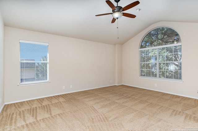 spare room featuring light colored carpet, vaulted ceiling, and ceiling fan