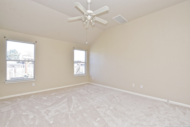 carpeted empty room with ceiling fan, a healthy amount of sunlight, and vaulted ceiling