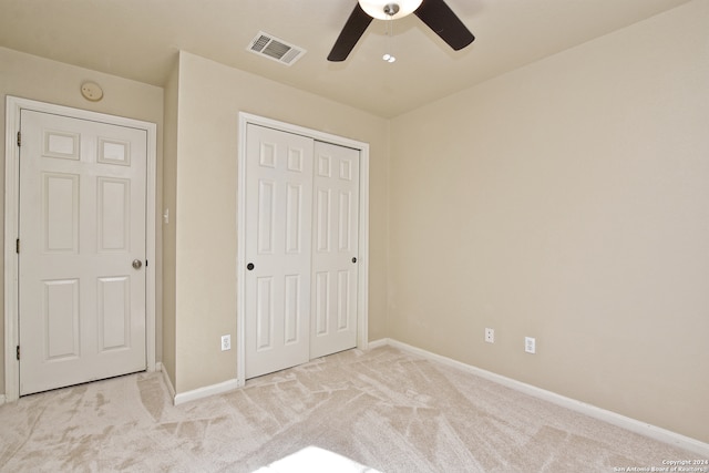 unfurnished bedroom with ceiling fan, light colored carpet, and a closet