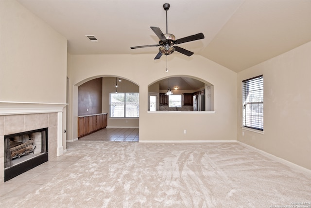 unfurnished living room with ceiling fan, light colored carpet, lofted ceiling, and a tile fireplace