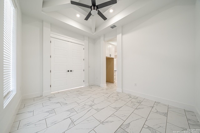 unfurnished bedroom featuring ceiling fan, a raised ceiling, and a closet