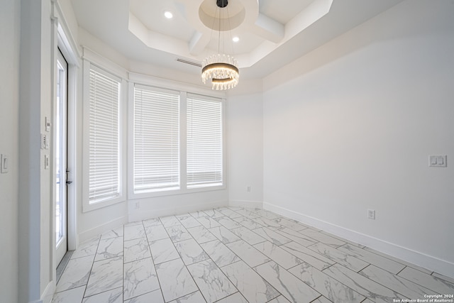 empty room with a raised ceiling and a chandelier