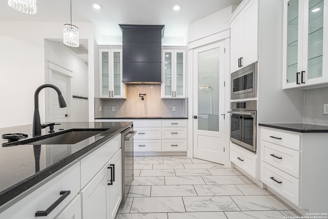 kitchen with appliances with stainless steel finishes, tasteful backsplash, sink, pendant lighting, and white cabinetry