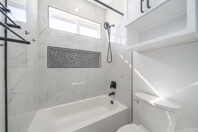 bathroom featuring tiled shower / bath combo and toilet