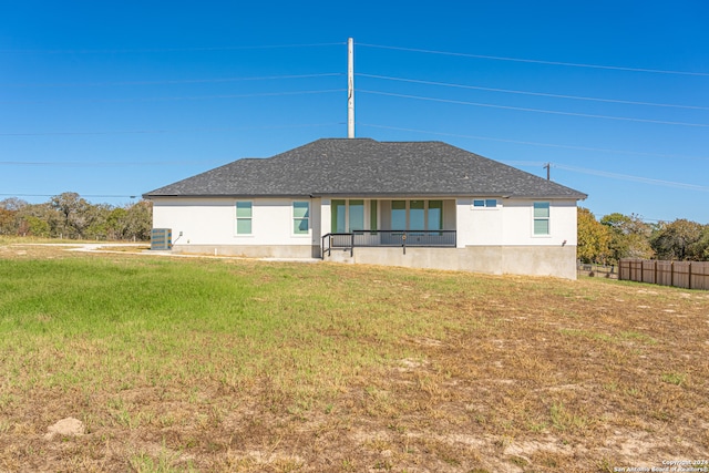 rear view of house featuring a lawn and central AC