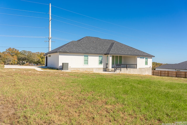 rear view of house featuring a lawn and central AC