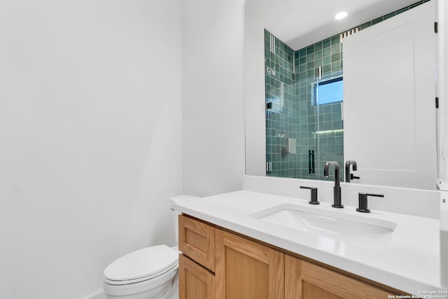 bathroom featuring vanity, toilet, and a shower with door