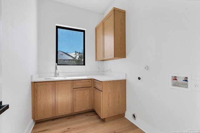 clothes washing area with electric dryer hookup, cabinets, sink, washer hookup, and light wood-type flooring