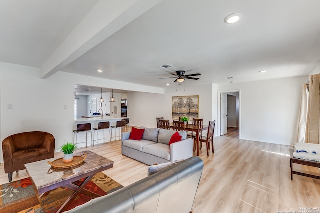 living room featuring beam ceiling, ceiling fan, and light hardwood / wood-style floors