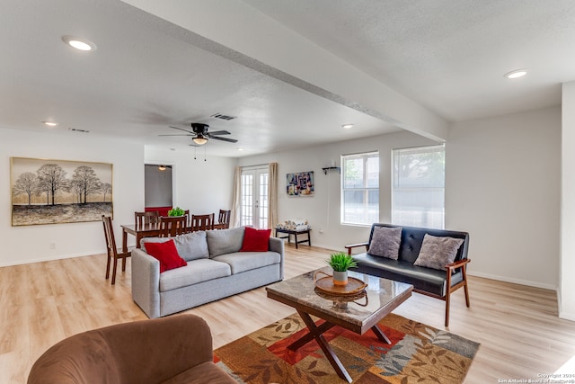 living room featuring ceiling fan, light hardwood / wood-style floors, a textured ceiling, and french doors