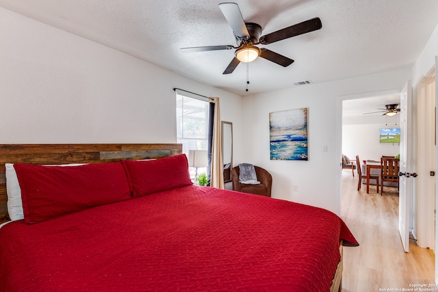 bedroom featuring a textured ceiling, light wood-type flooring, and ceiling fan