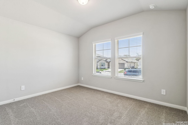unfurnished room featuring baseboards, lofted ceiling, and carpet