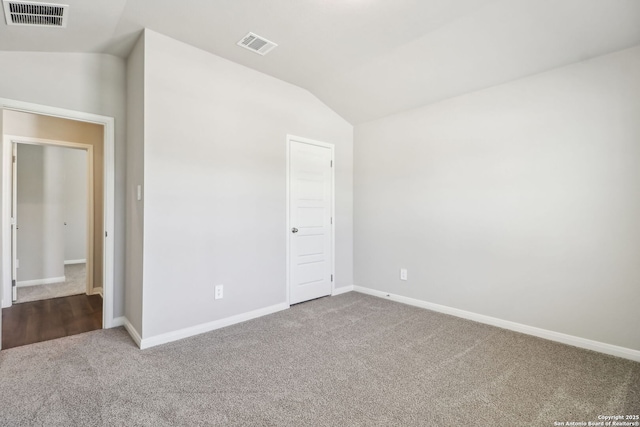 unfurnished bedroom with visible vents, carpet flooring, baseboards, and lofted ceiling