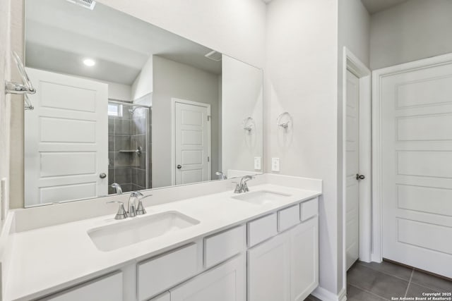 bathroom with tile patterned floors, a tile shower, double vanity, and a sink