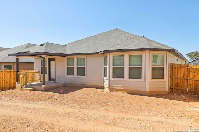 view of front of home with a shingled roof and fence