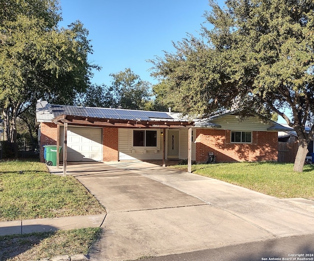 ranch-style house featuring a front lawn, a garage, and solar panels