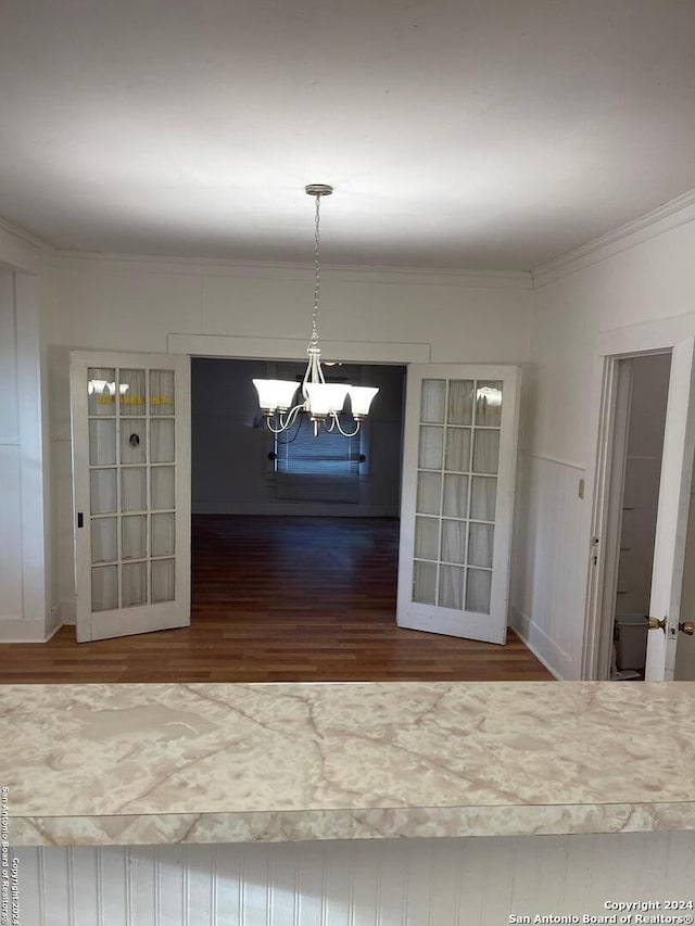 unfurnished dining area featuring wood-type flooring, ornamental molding, and a notable chandelier