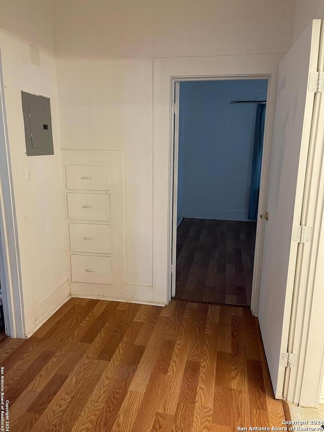 corridor with electric panel and wood-type flooring