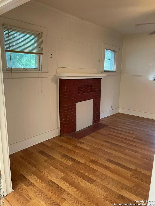 unfurnished living room with light hardwood / wood-style flooring, a healthy amount of sunlight, and a brick fireplace