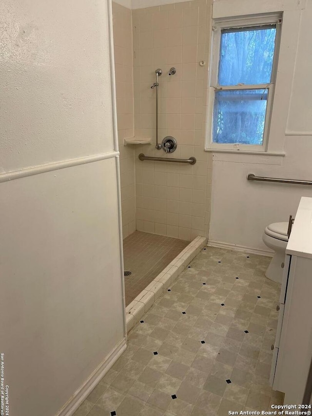 bathroom featuring a tile shower, vanity, and toilet