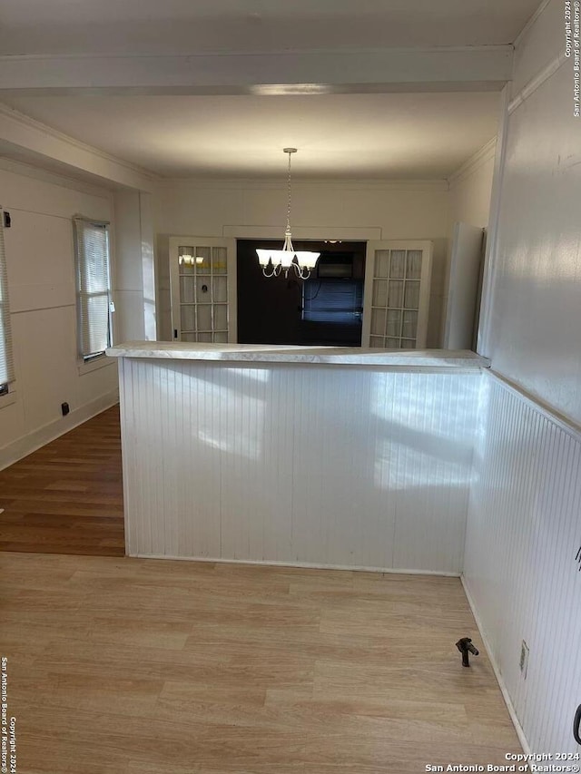 kitchen featuring pendant lighting, ornamental molding, a notable chandelier, and wood-type flooring