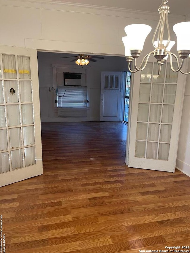 unfurnished dining area with ceiling fan with notable chandelier, dark hardwood / wood-style flooring, and crown molding