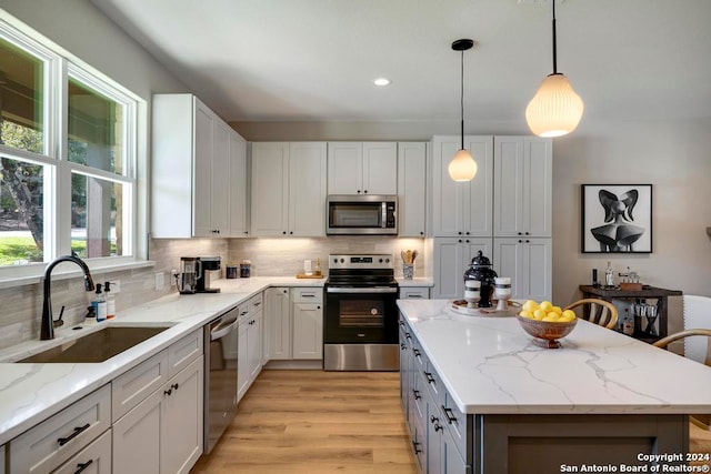 kitchen featuring appliances with stainless steel finishes, white cabinetry, hanging light fixtures, and sink