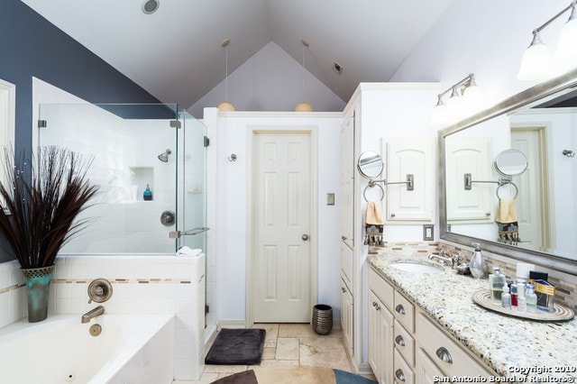 bathroom featuring vanity, separate shower and tub, and vaulted ceiling