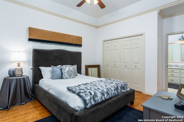 bedroom featuring a closet, hardwood / wood-style flooring, ceiling fan, and crown molding