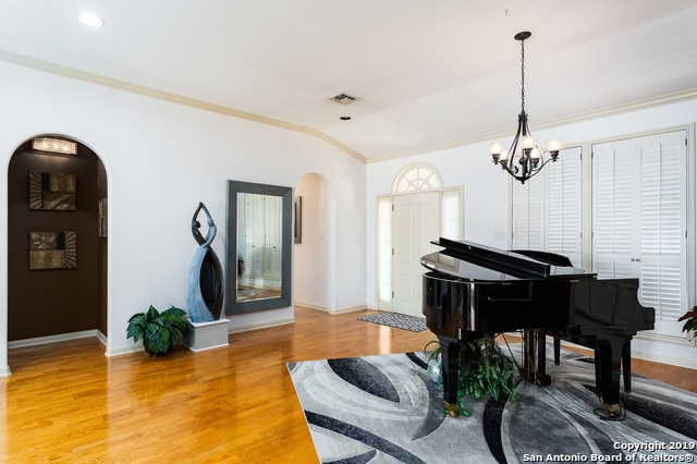 interior space with hardwood / wood-style flooring, ornamental molding, and an inviting chandelier