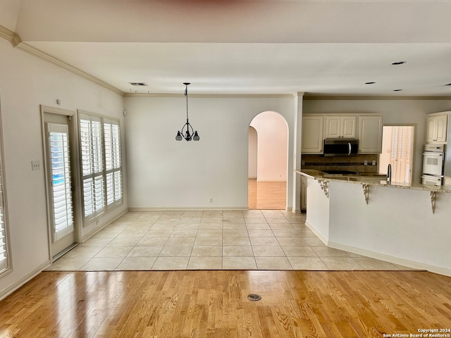 kitchen featuring light stone countertops, light hardwood / wood-style floors, white cabinetry, and a healthy amount of sunlight