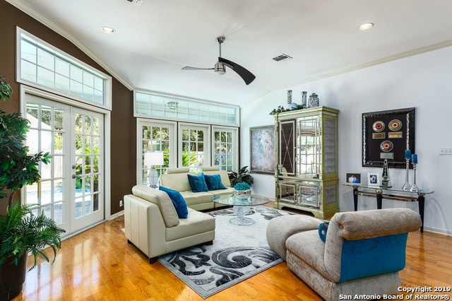 living room featuring light wood-type flooring, crown molding, a wealth of natural light, and french doors