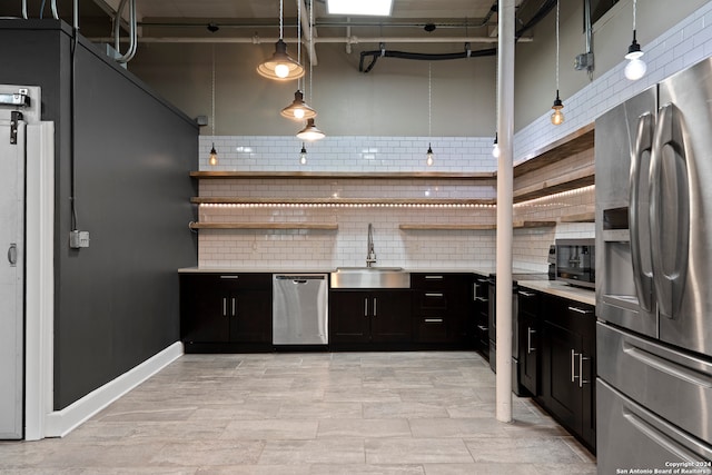 kitchen with sink, hanging light fixtures, backsplash, stainless steel appliances, and a high ceiling