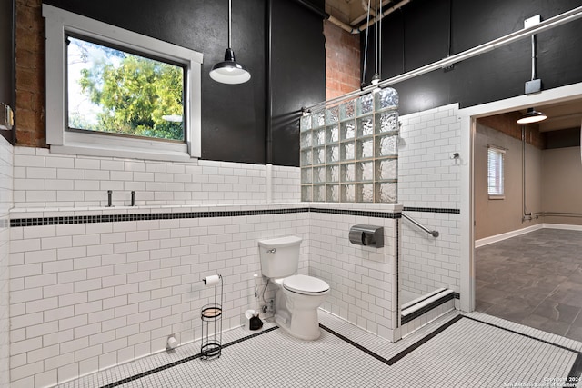 bathroom with tile patterned flooring, toilet, walk in shower, and tile walls