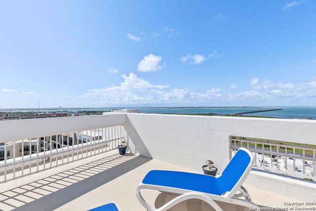 view of patio / terrace featuring a balcony, a water view, and a beach view