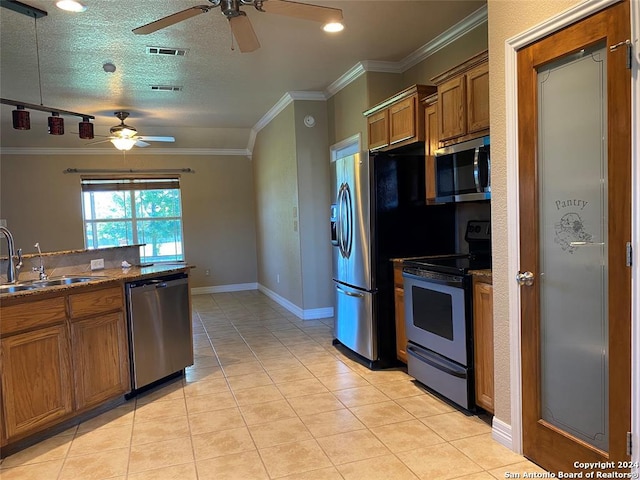 kitchen featuring sink, crown molding, a textured ceiling, light tile patterned floors, and appliances with stainless steel finishes