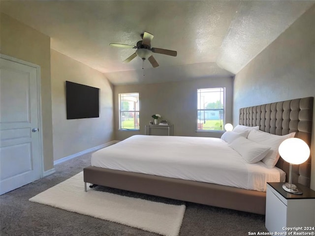 bedroom with ceiling fan, dark carpet, multiple windows, and vaulted ceiling