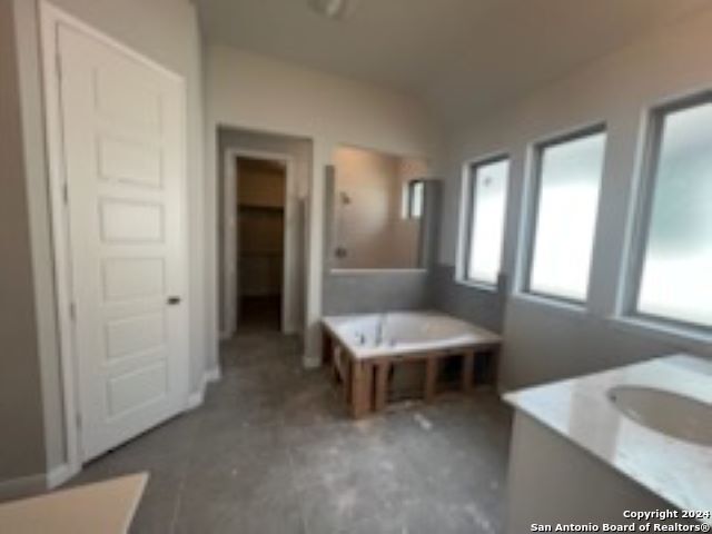 full bathroom with lofted ceiling, a garden tub, and vanity