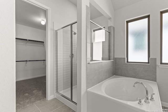 bathroom with a bath, a spacious closet, a shower stall, and tile patterned floors