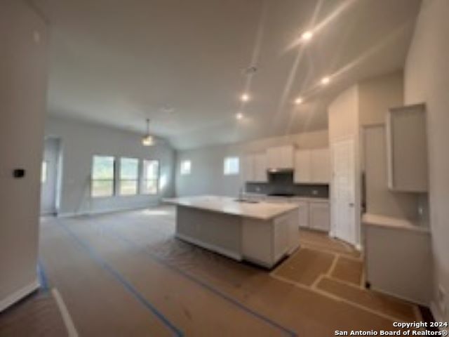 kitchen featuring a kitchen island, open floor plan, light countertops, white cabinetry, and pendant lighting