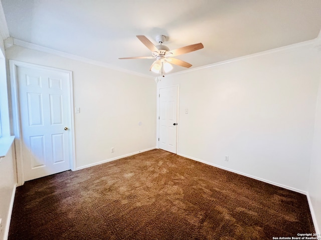 empty room featuring dark colored carpet, ceiling fan, and crown molding