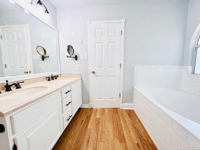 bathroom featuring hardwood / wood-style flooring, vanity, and tiled tub