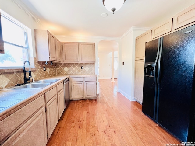 kitchen with decorative backsplash, light wood-type flooring, black refrigerator with ice dispenser, sink, and light brown cabinets