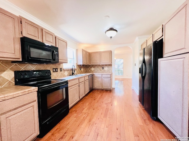 kitchen featuring light wood-type flooring, sink, ornamental molding, and black appliances