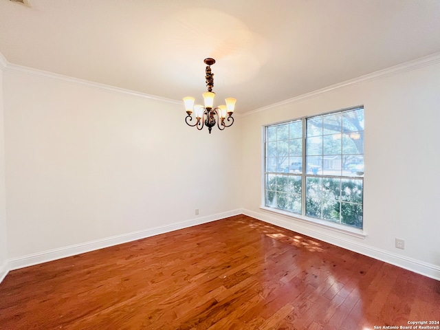 empty room featuring hardwood / wood-style floors, crown molding, plenty of natural light, and a notable chandelier