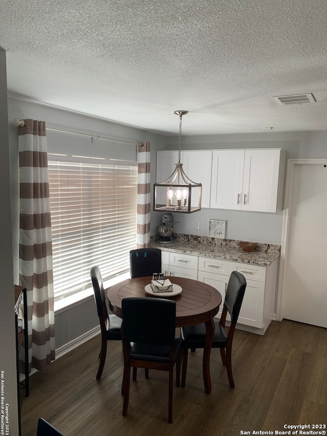 dining area with a notable chandelier, dark hardwood / wood-style flooring, and a textured ceiling