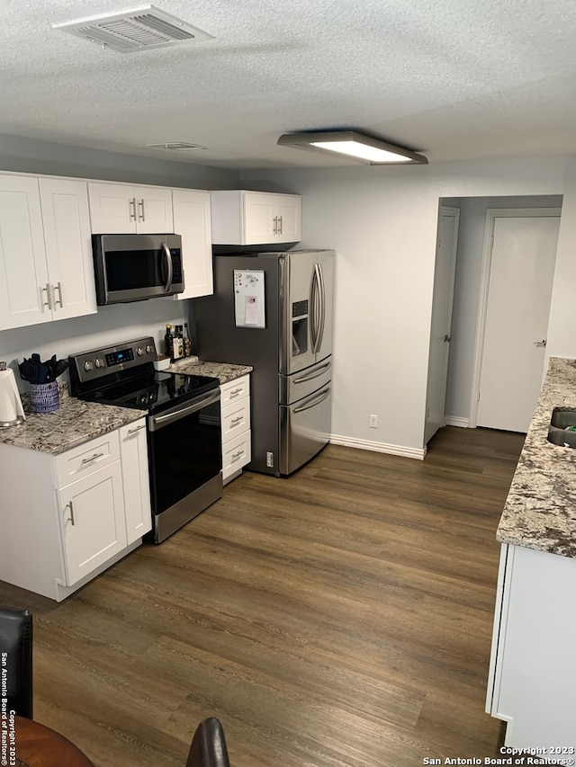 kitchen with white cabinetry, stainless steel appliances, light stone counters, dark hardwood / wood-style flooring, and a textured ceiling