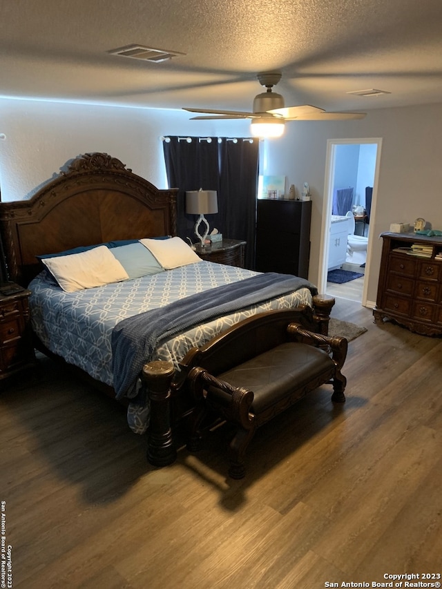 bedroom featuring ceiling fan, wood-type flooring, a textured ceiling, and ensuite bath