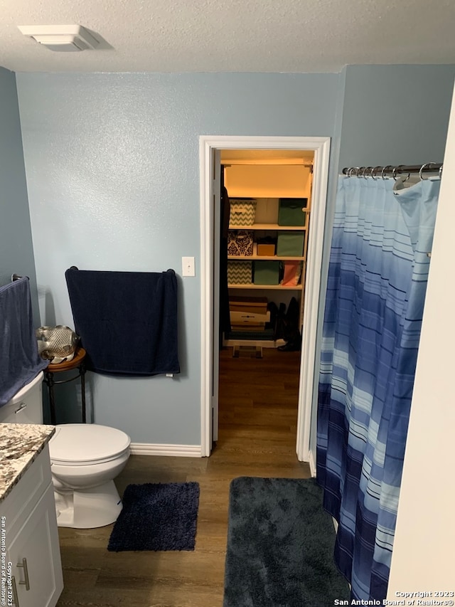 bathroom featuring vanity, toilet, wood-type flooring, and a textured ceiling